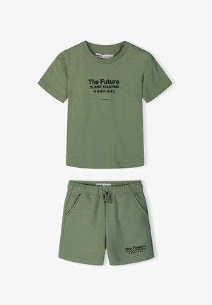 Zestaw składający się z zielonej koszulki z krótkim rękawem i szortów z elastyczną talią, z czarnym napisem "Przyszłość właśnie się zaczyna" oraz koreańskimi znakami na obu elementach.