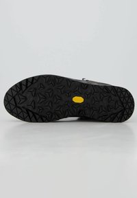 Suola in gomma nera con tacchetti multidirezionali e logo Vibram giallo. Superficie testurizzata per grip e stabilità.