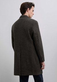 Abrigo de lana marrón oscuro con un patrón de espiga, ajuste entallado, solapas con muesca y puños de un solo botón. Cuenta con una abertura trasera para una mayor movilidad.