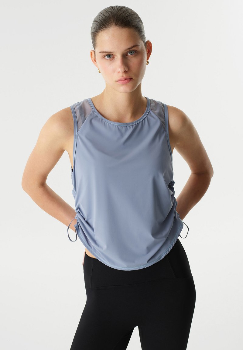 Lichtblauw mouwloos sporttopje met een gladde textuur, voorzien van een ronde halslijn en verstelbare zijstrikjes, gecombineerd met zwarte legging.