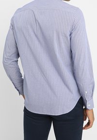 Hellblau kariertes Langarmhemd mit gebogtem Saum, geknöpften Manschetten und glattem Baumwollgefühl.