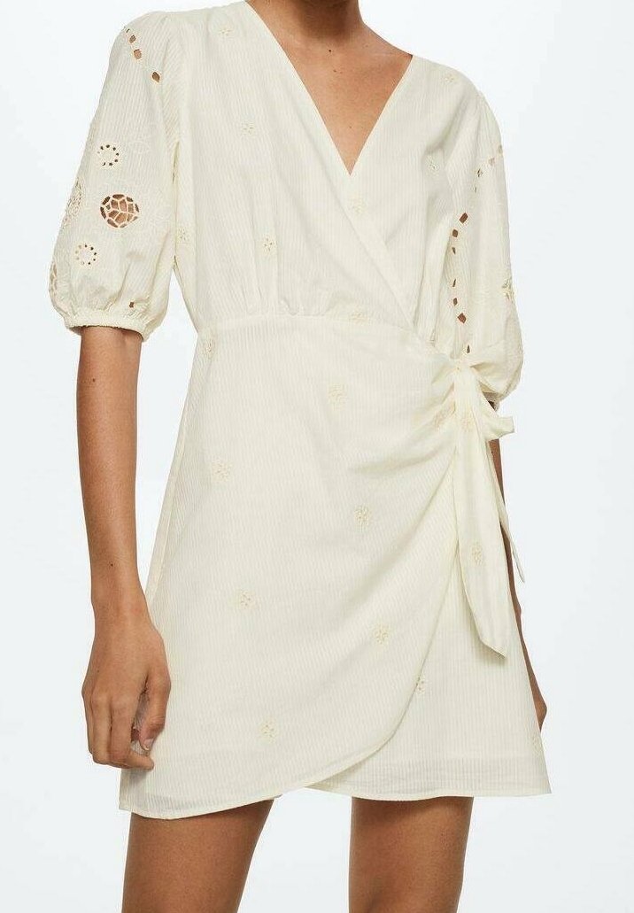 Cremefarbenes Wickelkleid mit tiefem V-Ausschnitt, kurzen Puffärmeln, strukturiertem Stoff und floralem Stickereidetails. An der Taille gebunden.