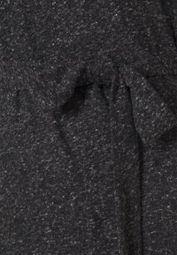 Mörkgrå, strukturerad tyg med ett subtilt prickigt mönster. Har ett knytband i midjan och mjuk drapering. Idealisk för avslappnade passformer.