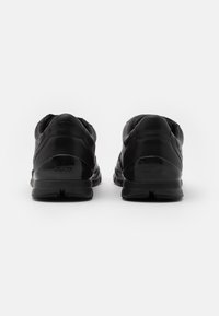 Svarta sneakers med en slät läderöverdel, vadderad krage och gummisula. Har Geox-logotyp på häldelen. Inga synliga accenter eller mönster.