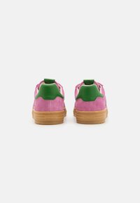 Pink suede sneakers with green accents and a beige rubber sole. Features a pull tab and textured finish on the upper.