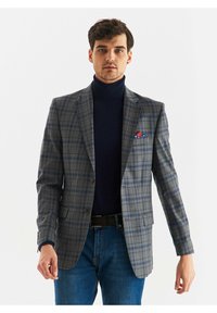 Szary marynarka w kratę z niebieskimi i czarnymi akcentami, z zapięciem na jeden guzik i poszetką. Nosi się na granatowym golfie.