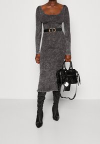 Szara, długosleeve sukienka o prążkowanej fakturze i okrągłym dekolcie, ściśnięta w talii czarnym paskiem. Noszona z czarnymi kozakami za kolano.