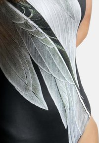 Zwart zwempak met een grote, gedetailleerde witte en groene veerprint aan één kant, met een gladde, gestructureerde stofafwerking.