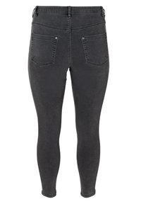 Musta farkut leggingsit, joissa on kapea muotoilu, keskikorkea vyötärö ja kaksi takataskua, jotka näyttävät sileältä, hieman haalistuneelta pinnalta.