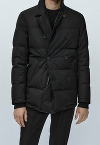 Giacca a vento nera con design doppiopetto, texture trapuntata e dettagli con bottoni. Presenta una tasca con zip e un colletto alto.