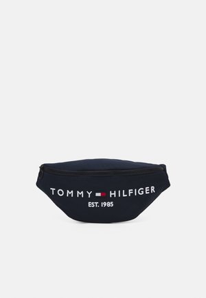 Granatowa nerka z czarnym zamkiem błyskawicznym, białym napisem "Tommy Hilfiger", czerwono-biało-niebieskim logo oraz napisem "EST. 1985" na przodzie.
