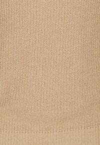 Tela de punto beige claro con un patrón texturizado, costuras uniformes y un dobladillo acanalado en la parte inferior.