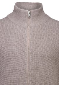 Ljust beige zip-up tröja med hög krage, strukturerat tyg med ett subtilt rutmönster och en silverfärgad dragkedjedetalj fram.