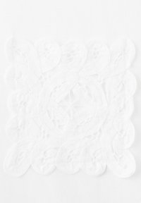 Pătrat delicat din dantelă albă cu modele florale și frunze detaliate, așezat pe o suprafață albă plată, evidențiind detaliile fine ale broderiei.