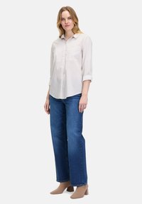 Light pink striped shirt with a button-up design, rolled sleeves, paired with dark blue wide-leg jeans and beige block-heel shoes.