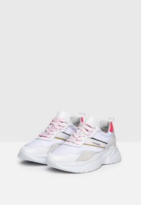 Weiße Sportschuhe mit einer Mischung aus Netz- und Wildledermaterialien, rosa Akzenten und einer klobigen Sohle mit schwarzen und gelben Streifen.