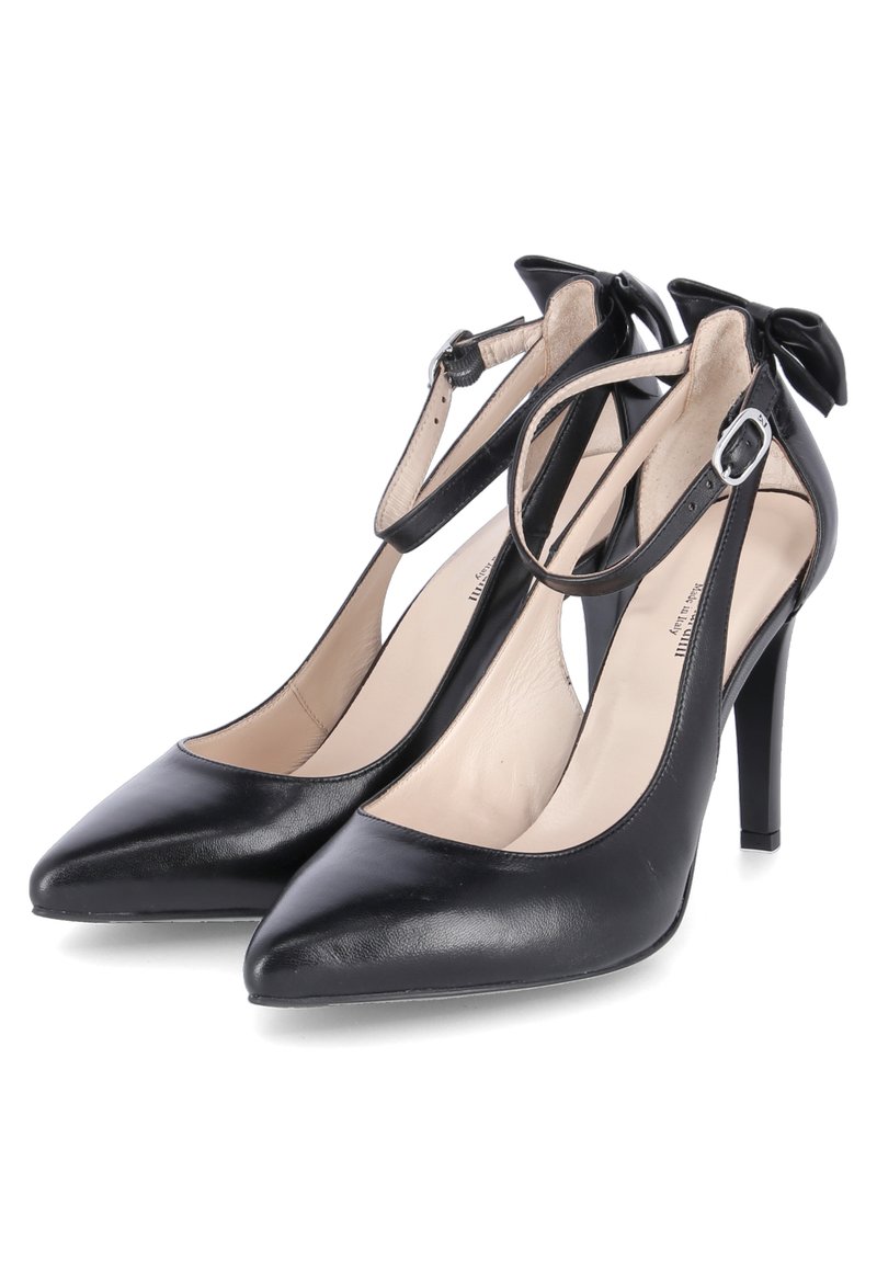 Zwarte leren high-heeled pumps met spitse neuzen, enkelbandjes en kleine strikdetails op de hak. Gladde textuur, strak ontwerp.