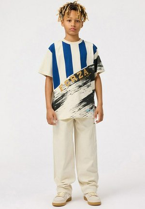 Kortärmad t-shirt med blå och vita ränder, prydd med en svart penseldragsdesign och texten "FORZA". Kombinerad med beige cargobyxor.