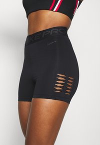 Czarne szorty Nike Pro o dopasowanym kroju, z szerokim elastycznym paskiem w talii i wyciętymi wzorami po bokach. Gładki, elastyczny materiał.