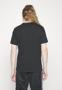 Fekete, rövid ujjú póló, kerek nyakkal, puha anyagból készült. Sima textúrájú, normál fazonú, látható minták vagy grafikák nélkül.