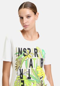 T-shirt blanc à manches courtes arborant une impression colorée "Inspiré par la Nature" avec des feuillages et des fleurs. Tissu doux avec un col rond.