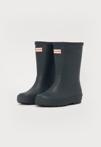 Bottes de pluie en caoutchouc noir jusqu'à la cheville avec une semelle texturée et des rayures rouges et blanches avec le logo "HUNTER" à l'avant. Fini lisse, bout arrondi.
