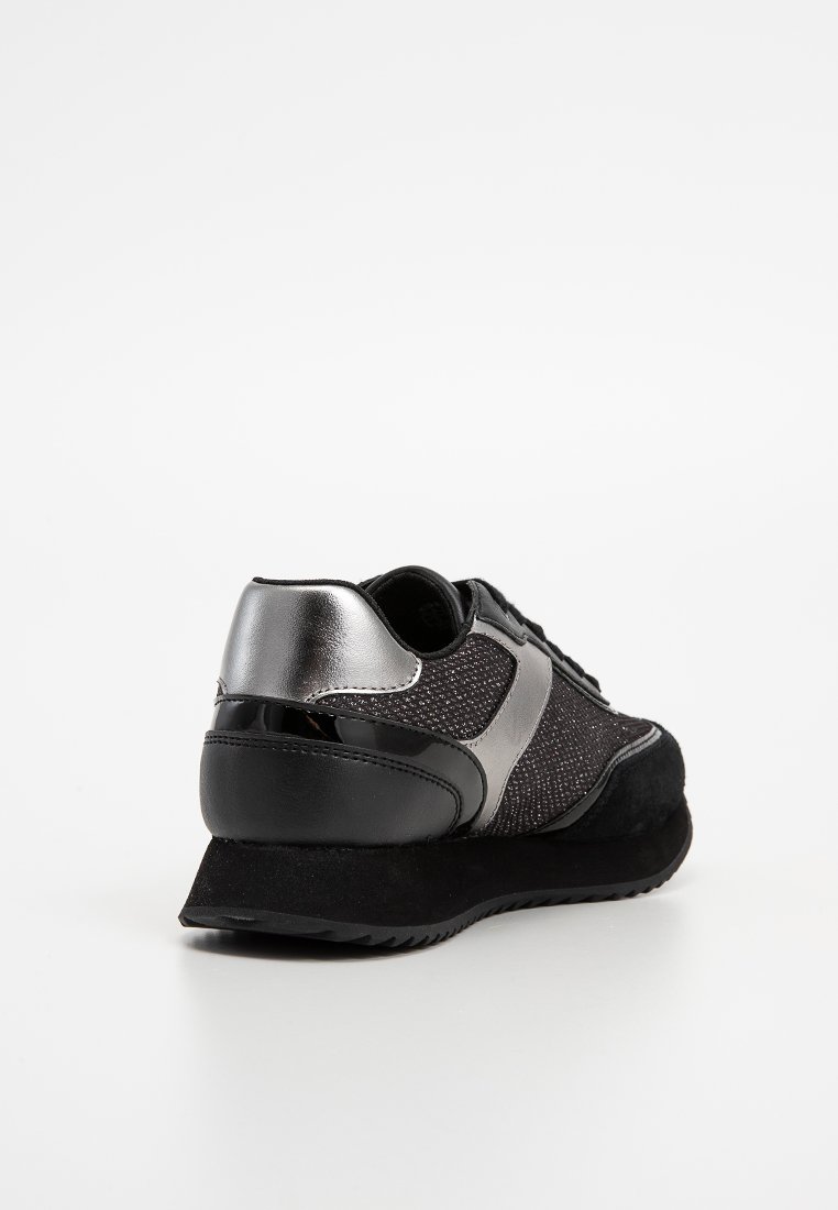 Schwarzer und silberner Sportschuh mit einem strukturierten Mesh-Obermaterial, glatten Lackdetails und einer gepolsterten schwarzen Sohle mit leichtem Absatz.