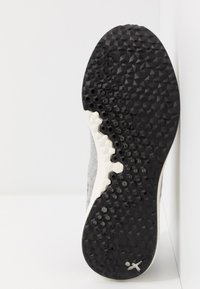 Semelle de chaussure avec un motif en caoutchouc noir texturé et des grips hexagonaux. Tissu supérieur gris avec un accent de semelle intermédiaire blanche. Design plat.