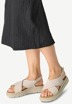 Sandalias beige con tiras cruzadas, con una plantilla texturizada y suelas de goma anchas, que cuentan con una correa ajustable en el tobillo y un diseño minimalista.