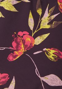 Květinová látka v tmavě fialové barvě, s jasně růžovými a žlutými květy a zelenými listy, texturovaný povrch s jemným vzorem.