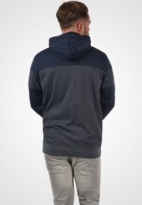 Felpa con cappuccio blu navy e grigia, con un corpo testurizzato, maniche lisce e una tasca a marsupio, dotata di coulisse sul cappuccio.