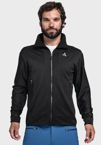 Schwarze Zip-Jacke mit hohem Kragen, ausgestattet mit seitlichen Reißverschlusstaschen und einem Logo auf der linken Brust. Glattes Material mit strukturierter Oberfläche.