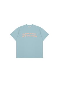 Light blue cotton short-sleeve t-shirt featuring bold, curved text in pink: "LEGACY STUDIOS." Simple design with a relaxed fit.