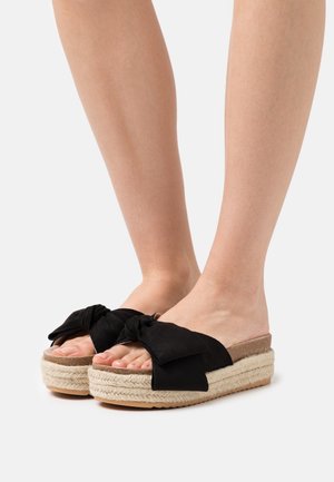 Zwarte espadrille platform sandalen met een gestructureerde jute zool en een grote strikaccent aan de voorkant. Open teen ontwerp.