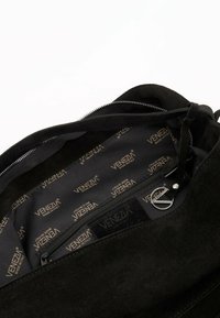 Zwarte suède handtas met een ritsluiting, gladde textuur en binnenvoering met het herhaalde "Venezia" logo in goud. Inclusief een ritsvak.
