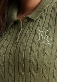 Olivově zelený pletený polo trikot s texturovaným kabelkovým vzorem, žebrovaným límcem a jemně vyšitým logem na hrudi.