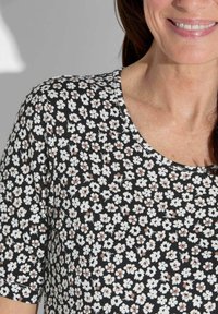 Zwarte shirt met korte mouwen met een bloemenpatroon in wit en blush, met een ronde halslijn en zachte, lichtgewicht stof.