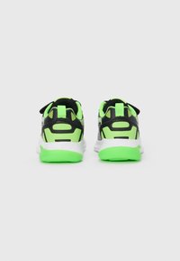 Des chaussures de sport noires et vert néon avec une texture lisse, dotées d'une semelle rembourrée et d'une languette au niveau du talon pour un enfilage facile.