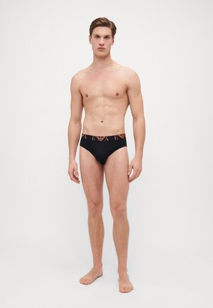 Bañadores negros con cinturilla de logo y detalles en naranja, fabricados en tejido elástico, diseñados para una silueta ajustada.