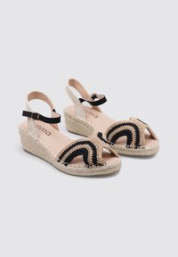 Sandalias de cuña con una plataforma de paja trenzada, diseño de ganchillo en negro y beige, correa ajustable en el tobillo y un suave forro interior.