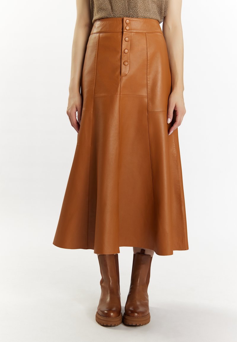 Brown leather maxi skirt with a high waist, five buttons down the front, and a flared silhouette. Worn with matching brown heeled boots.