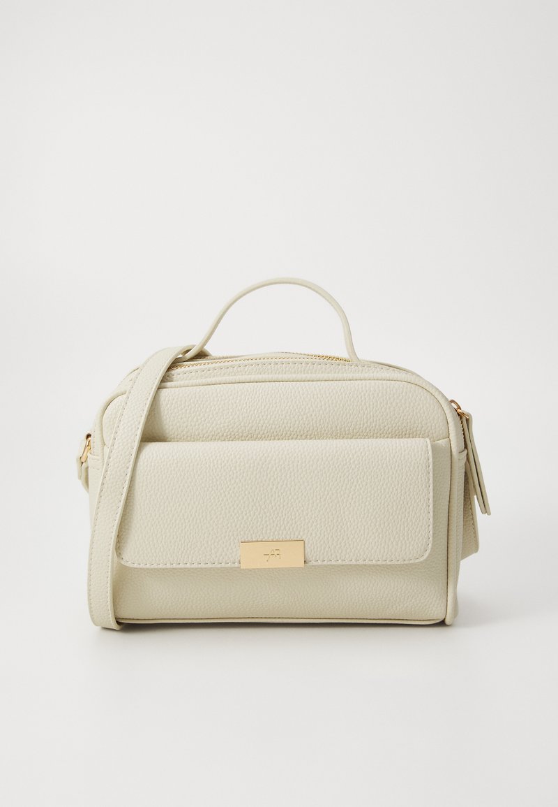 Petit sac bandoulière crème en cuir texturé. Avec une poche à rabat à l'avant et un accent en métal doré. Fermeture éclair.