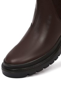 Bruine leren enkelboot met een panel van textuurstof, ronde neus en zwarte rubberen zool met een profiel voor grip.