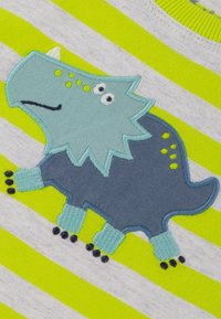 Grau und hellblau gestreiftes Kleidungsstück mit einer Dinosaurier-Stickerei, die einen stacheligen Kamm, kleine Füße und schwarze Akzente auf einem hellgelben Hintergrund zeigt.