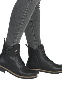 Bottes chelsea en cuir noir avec une tête arrondie, fermeture à lacets et zippée, semelle texturée et semelle intermédiaire contrastante beige.