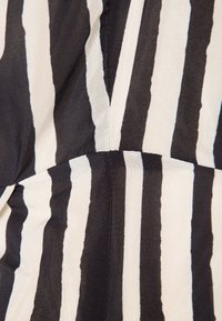 Gros plan sur un tissu rayé vertical noir et blanc avec une couture et une texture subtile, montrant des plis drapés.