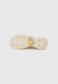 Schuhsohle mit einem strukturierten Design, in Beige gehalten und einem auffälligen gelben Vibram-Logo, aus strapazierfähigem Gummi gefertigt.