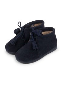 Botines de ante azul marino con una textura suave, punta redondeada y adornos de borlas decorativas. Suela de goma con detalle de costura a lo largo de los bordes.