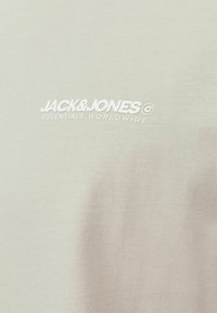 Lys grå bomulds T-shirt med teksten "JACK & JONES ESSENTIALS WORLDWIDE" i hvid broderi på forsiden.