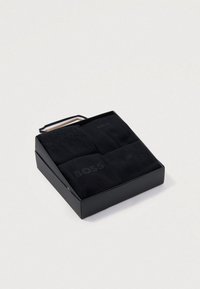 Conjunto de meias pretas em uma caixa preta, com quatro pares de meias com discreta marcação "BOSS", textura suave e sem padrões visíveis.